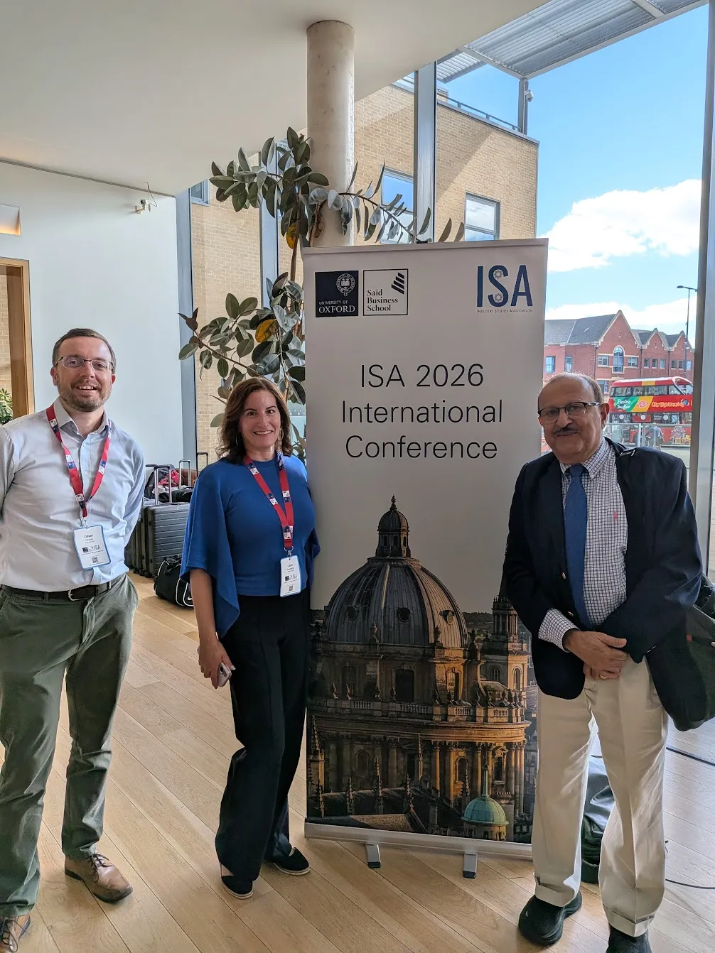 Ollie, Caryn and Nitin standing beside the ISA 2026 International Conference banner at Saïd Business School, Oxford